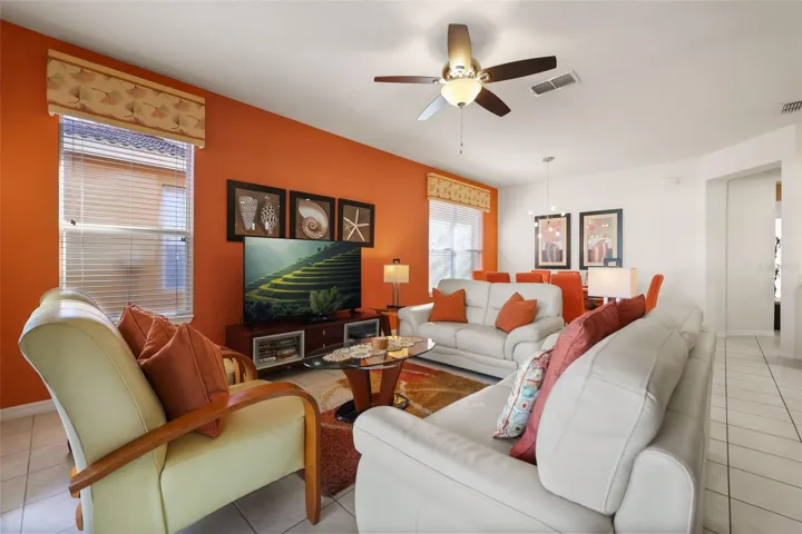 Open-concept living room featuring comfortable furnishings, abundant natural light, and seamless flow into the dining area.