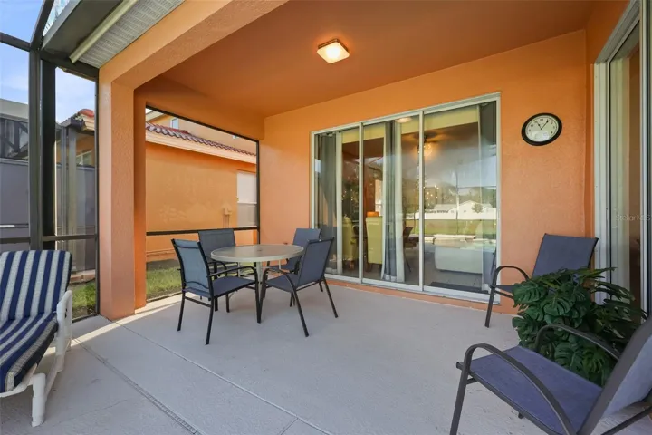 Covered lanai with outdoor dining area, perfect for al fresco meals and relaxing beside the pool.