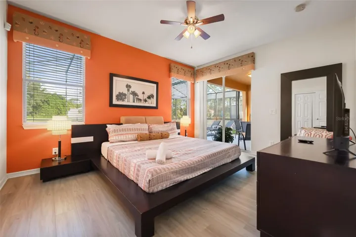 Spacious primary suite featuring a king-size bed, vaulted ceiling, and sliding glass doors opening directly to the pool deck.