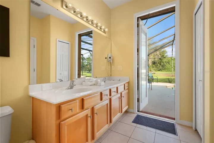 Primary en-suite bathroom featuring a dual-sink vanity and direct access to the pool deck for added convenience.