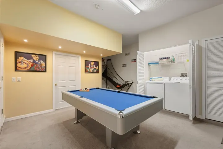 Garage games room complete with a pool table, basketball game, and laundry area for added entertainment.