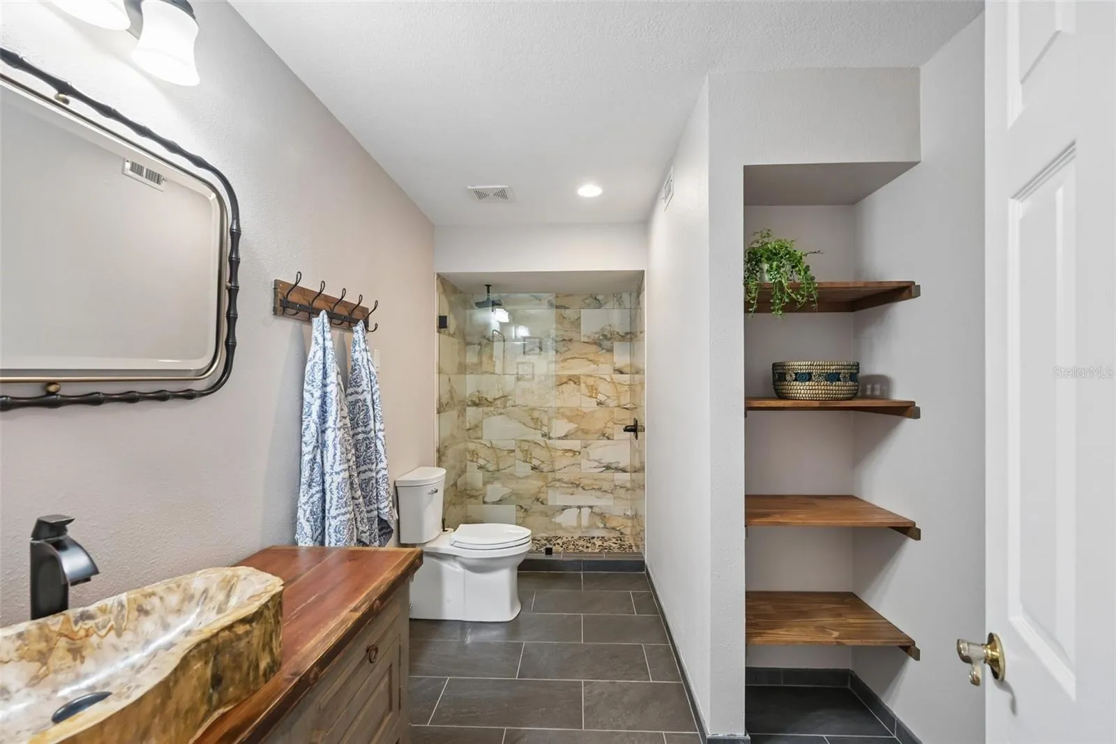 Second bathroom on 1st floor with stone sink and rain shower.
