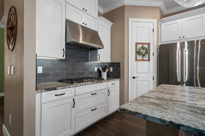 A natural stone backsplash and the highly upgraded Leathered Granite adds to the sophistication of the Kitchen. Please take notice of the large drawers under the cooktop.