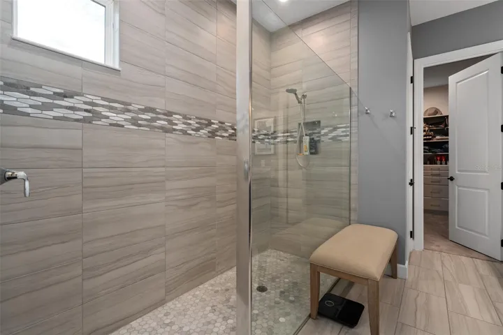Primary En-Suite Shower featuring Upgraded Floor to Ceiling Wall and Floor Tile with Listello Double Row Accent.