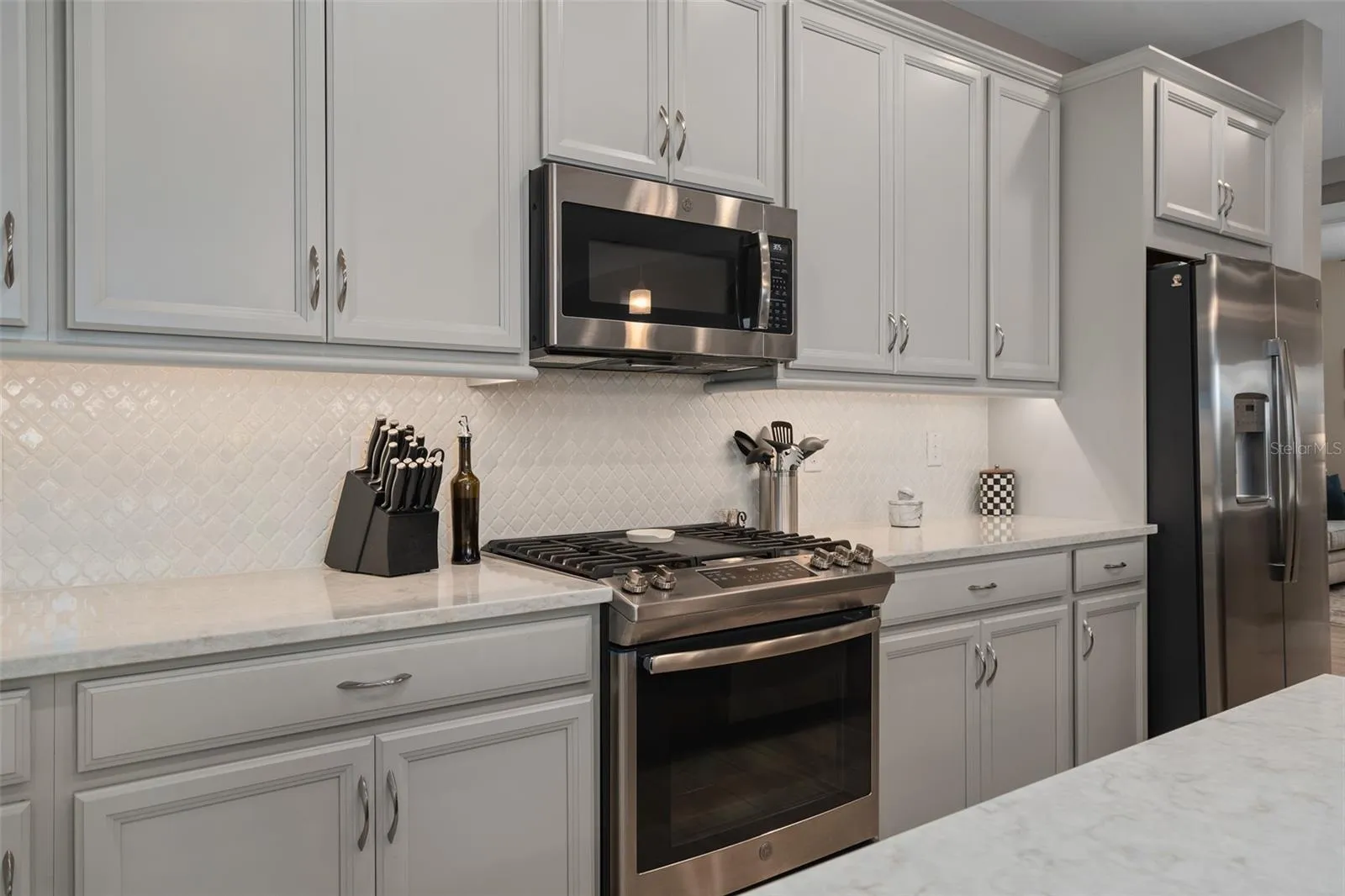 Solid Wood Cabinetry with Under Cabinet Lighting, a Built-In Refrigerator Wall Cabinet and a Ceramic Backsplash