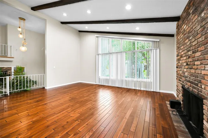 An impressive living space highlighted by soaring beamed ceilings, a substantial fireplace, and beautifully finished hardwood flooring