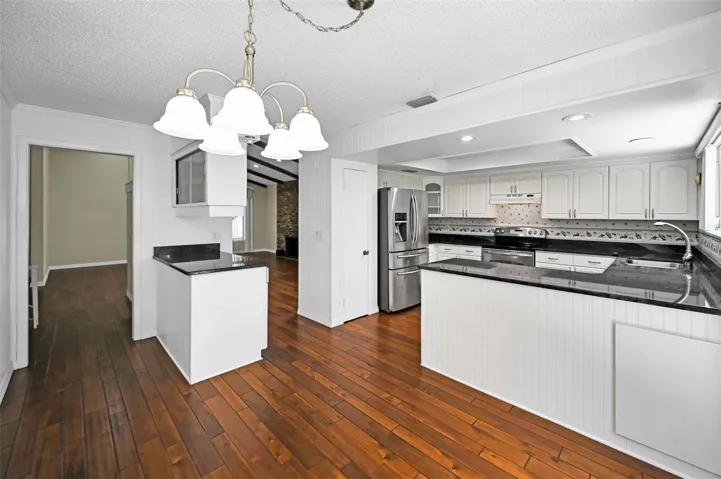 Updated kitchen featuring shaker cabinets and open sightlines to the dining and family spaces
