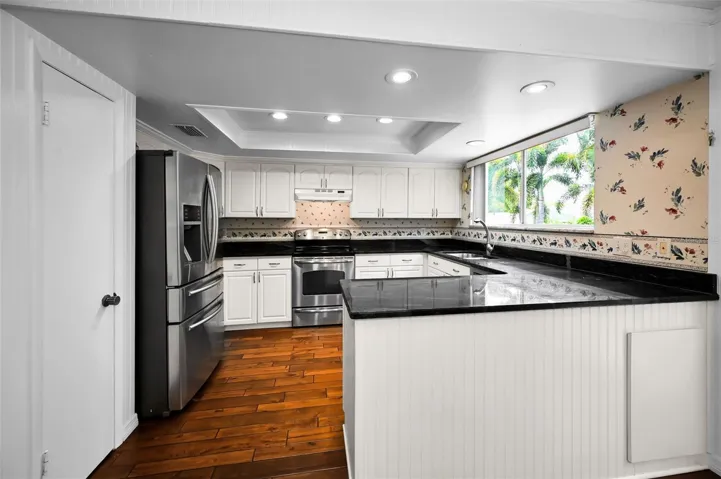 A refreshed contemporary kitchen with shaker cabinets and seamless flow into the dining and family rooms and overlooking the backyard.