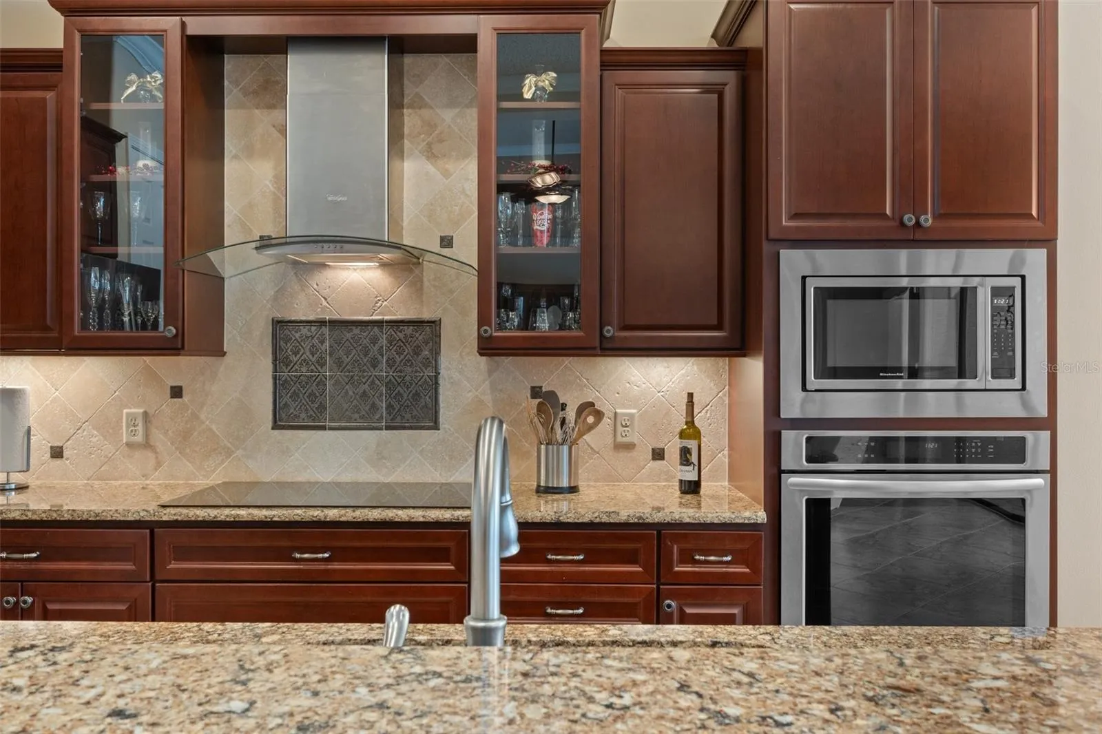 Upgraded finishes throughout the home add to its beauty. The professional Hood Vent, Tile Backsplash, glass front display cabinets, and under cabinet lighting add to the inviting appeal of the kitchen.