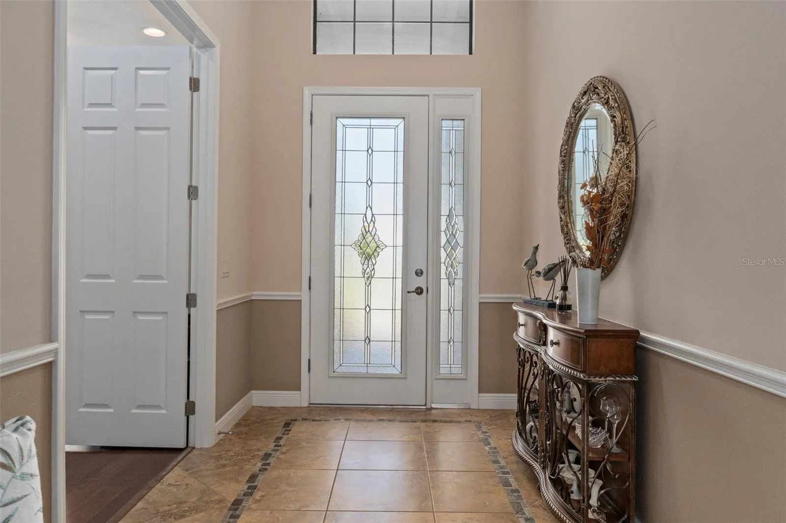 The spacious entry is bathed in natural light through the leaded glass front door. The doorway to the left features 2 solid French doors and leads into the flex room, currently used as a den, but could easily become a 3rd bedroom.