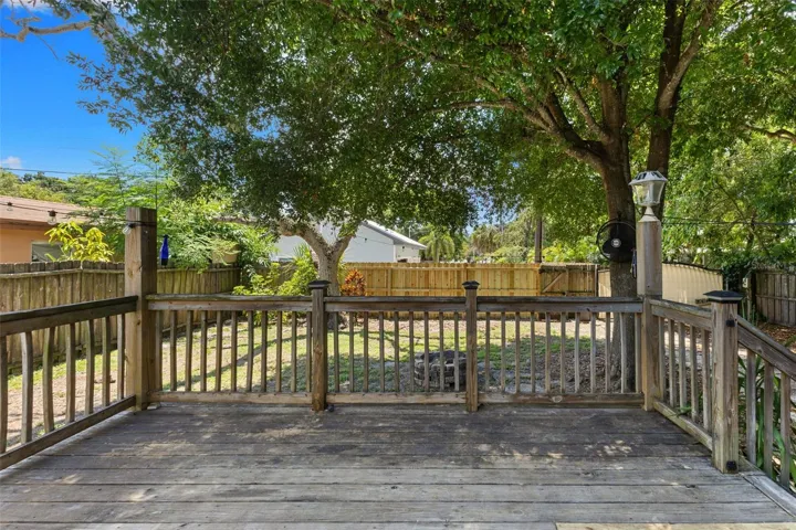 The home's rear elevation with an inviting deck, new privacy fencing, and a shaded, pet-friendly yard.
