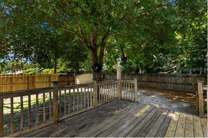 Spacious back deck overlooks a fully fenced yard with a built-in stone fire pit — ideal for Florida entertaining under mature shade trees.