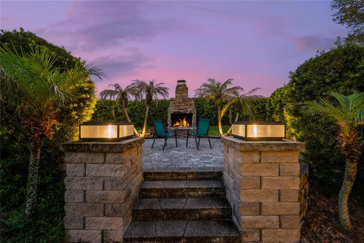 Backyard Retreat- Beautifully designed raised paver gathering space anchored by a grand wood-burning fireplace.