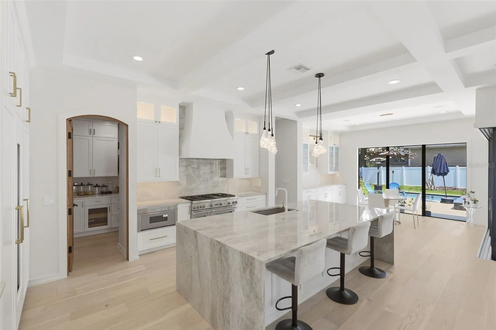 Kitchen features crystallized quartzite counters, oversized waterfall island &amp; walk-in panty