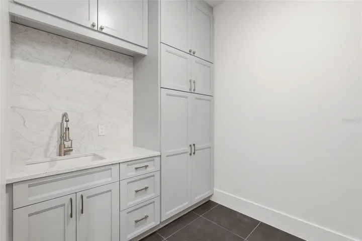 Upstairs laundry room with custom cabinets & utility sink