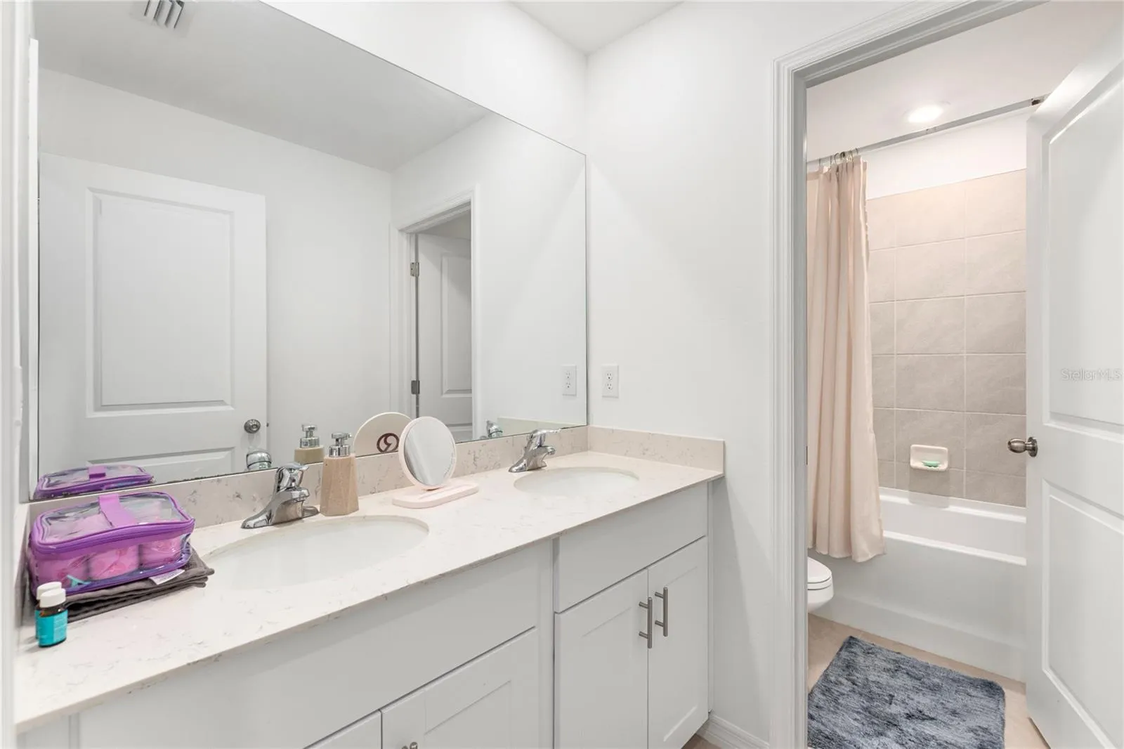 Modern guest bathroom with dual sinks and quartz countertops.