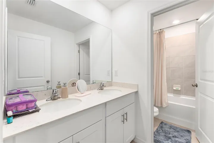 Modern guest bathroom with dual sinks and quartz countertops.