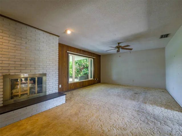 Fireplace with brick surround, raised hearth, and picture window
