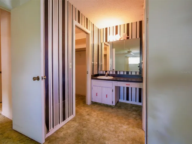 Primary bath with vanity, mirrored wall, and closet access