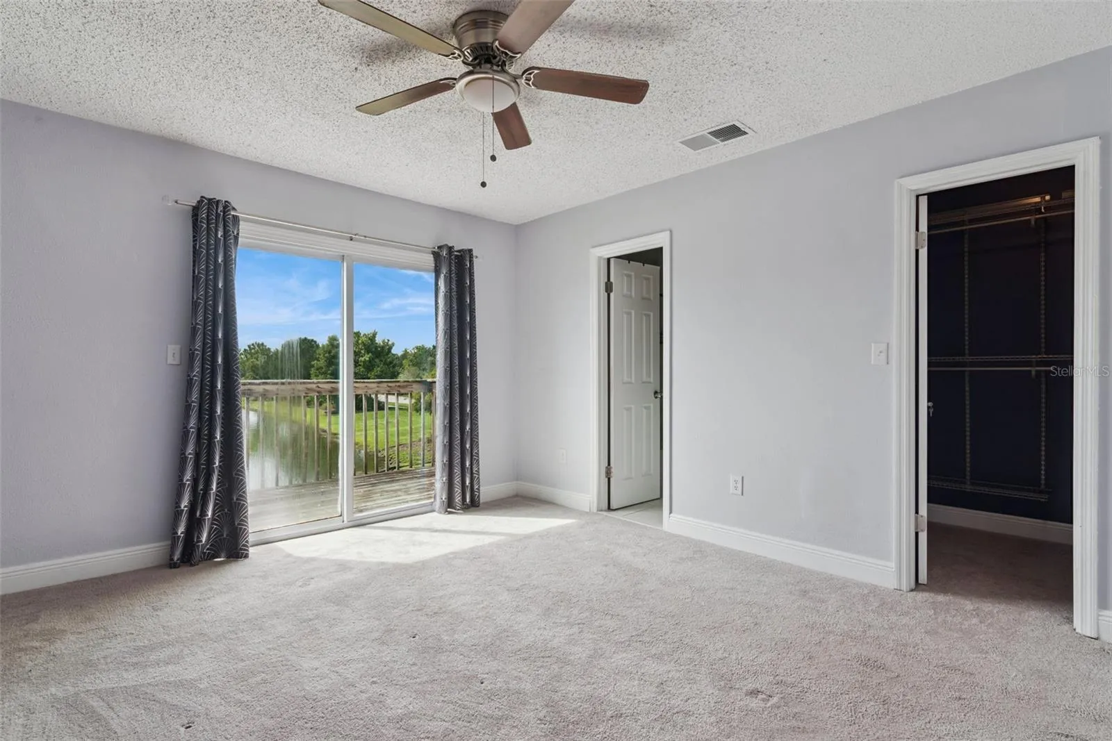 Primary Bedroom with view to the Balcony that overlooks the pond