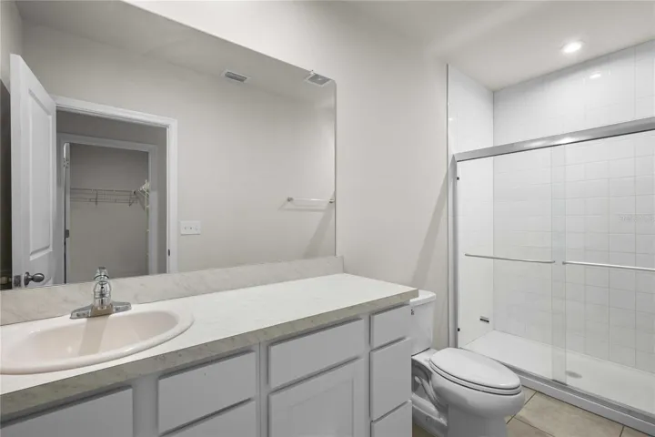 The primary bath with tiled floors and shower surround has new glass doors