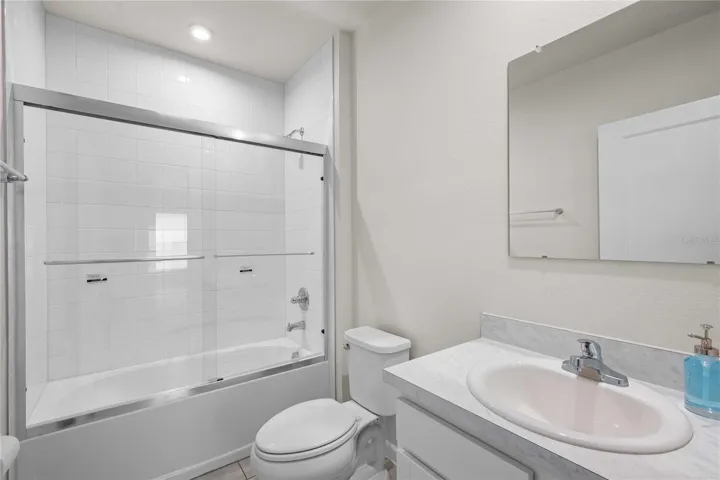 The guest bath has a tub with tile shower surround and a new glass sliding door