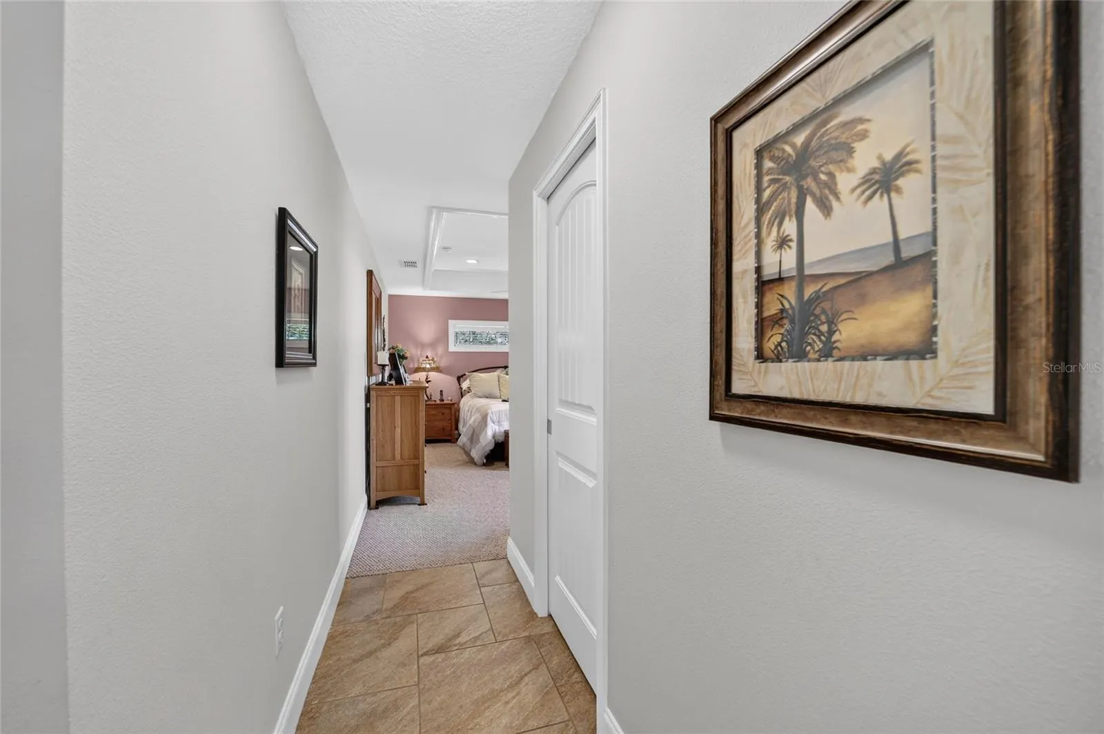 Hallway to primary bedroom with pocket-door to closet on right