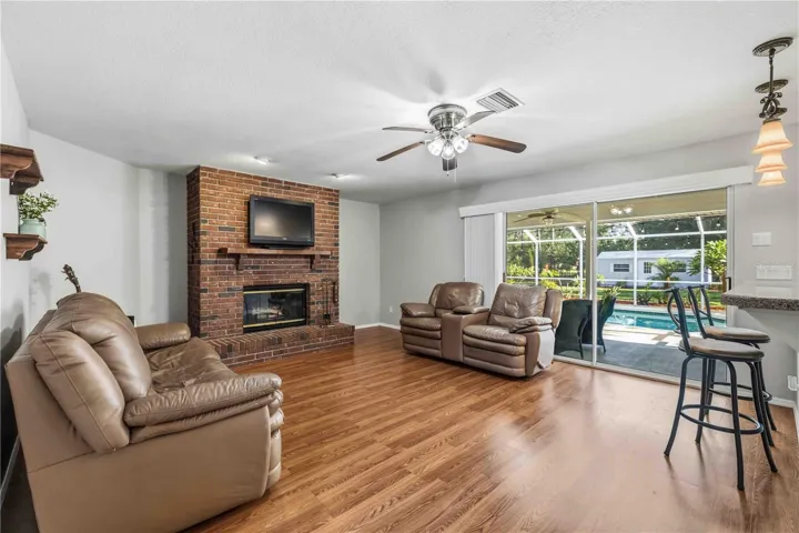 Family Room with wood burning fire place and relaxing views to the Lanai and Pool (shed/workshop behind)