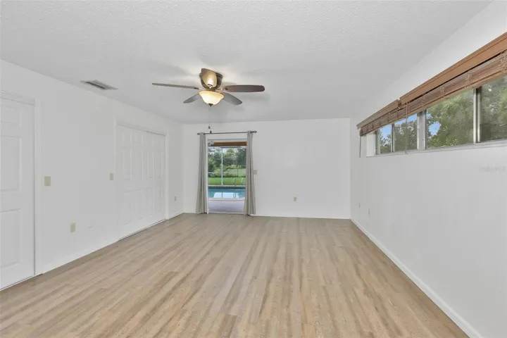 Primary Bedroom has a full wall closet system, high windows for security and a view onto the pool.