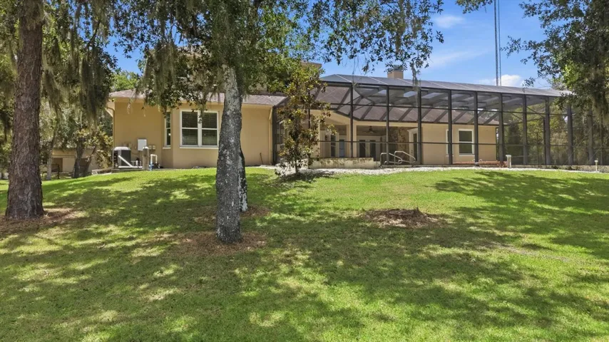 Rear lawn and screened pool area on the wooded acreage