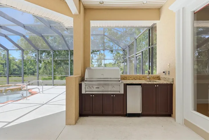 Outdoor kitchen and bar area beside the screened pool
