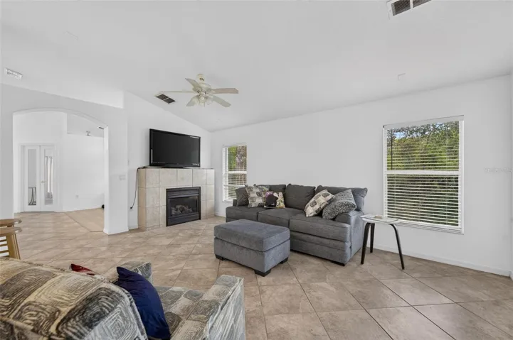 View of luxurious natural GAS burning fireplace, natural light with windows and sliders to patio