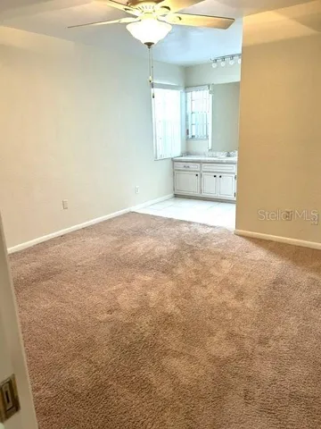 Primary bedroom w/ vanity which is adjacent to the primary bathroom out of sight on right,