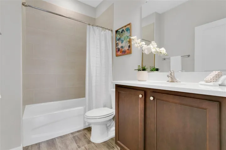 Downstairs bathroom with quartz countertop and tiled bath/shower combo.