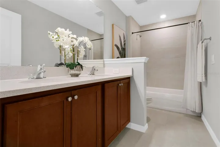 Upstairs secondary bath with quartz countertops and tiled shower.