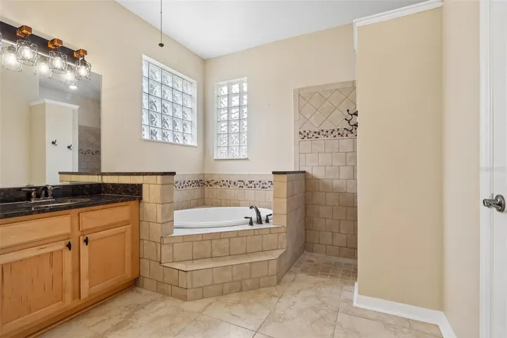 A SPA-INSPIRED EN SUITE BATH is complete with dual sinks with makeup station, a relaxing ROMAN TUB, an oversized walk-in tiled shower with built-in bench, and a private water closet.