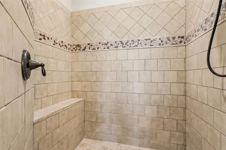 A SPA-INSPIRED EN SUITE BATH is complete with dual sinks with makeup station, a relaxing ROMAN TUB, an oversized walk-in tiled shower with built-in bench, and a private water closet.