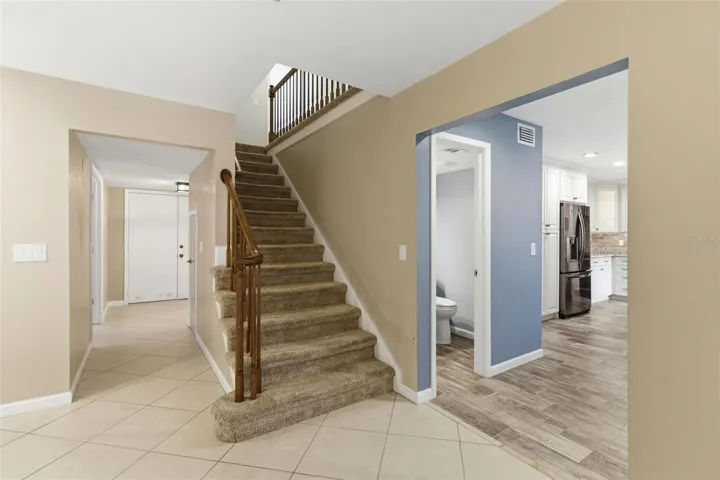 View of entry doors, half bath, kitchen and stairs