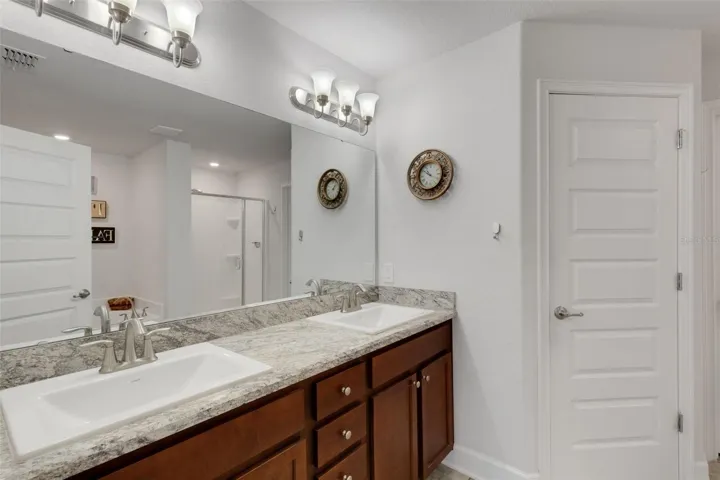 The ensuite bathroom features a long vanity with plenty of storage and dual sinks.