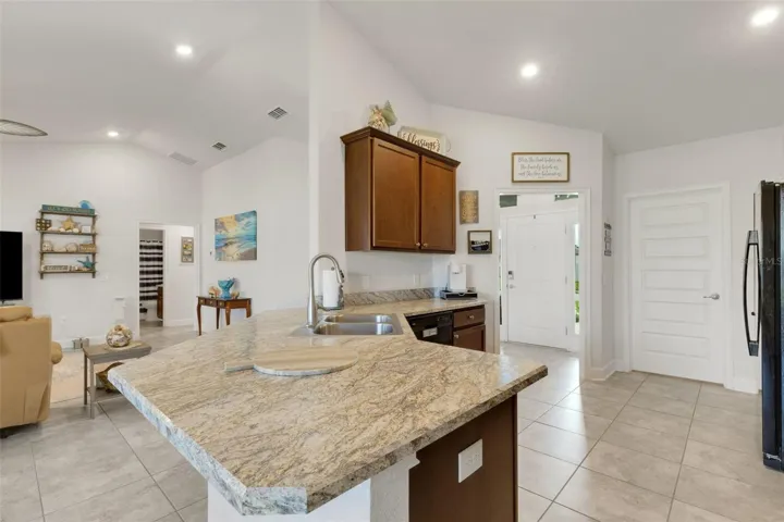 Solid surface countertops and two-bowl stainless steel sink with gooseneck pulldown faucet.