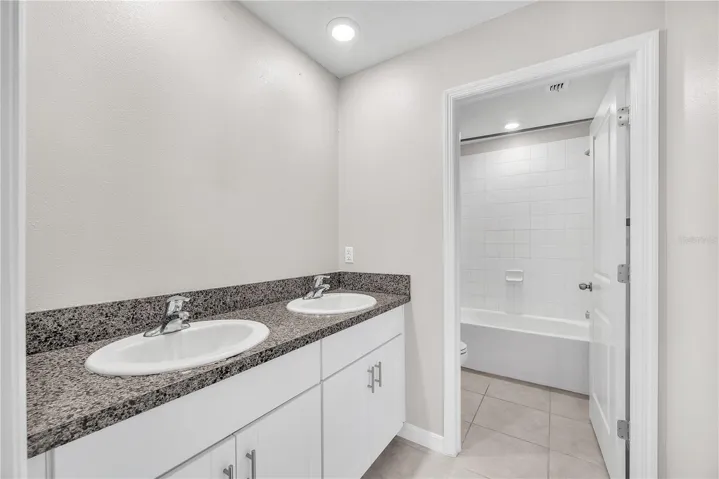 Jack & Jill bathroom with dual sinks and separate room with tub/shower combination and toilet.