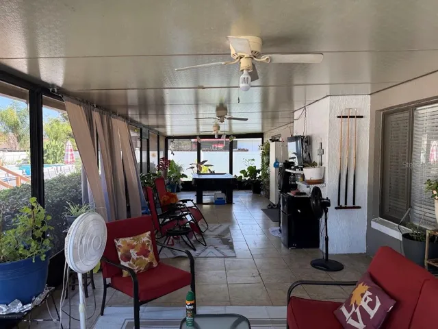 Oversized covered/screened back porch, tile flooring, ceiling fans, and pool table overlooking fenced backyard and above ground pool.
