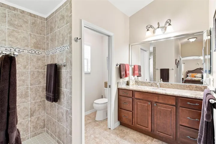 Primary Bath features double vanity sinks, granite countertops, and walk in tiled shower.