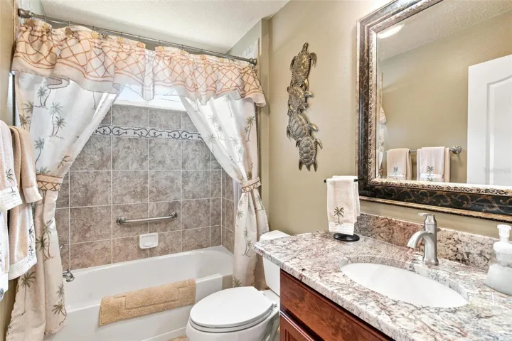 Guest bathroom features granite countertops and a shower/tub combo.