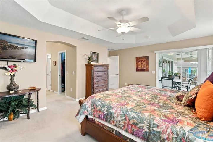 Primary Suite features trey ceilings, sliders to screen enclosed lanai, 2 walk in closets, and primary bath.