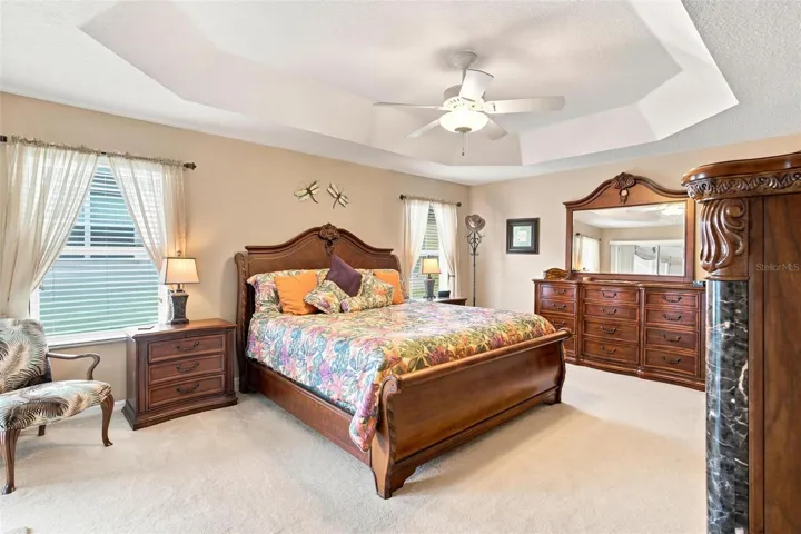 Primary Suite features trey ceilings, sliders to screen enclosed lanai, 2 walk in closets, and primary bath.