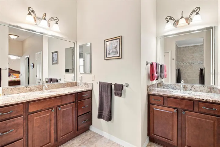 Primary Bath features double vanity sinks, granite countertops, and walk in tiled shower.