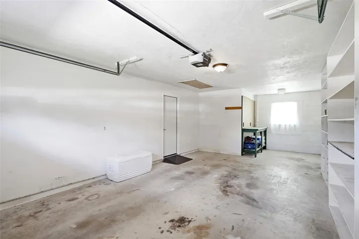 Oversized one-car garage w/additional storage at rear. Shelving units stay.
