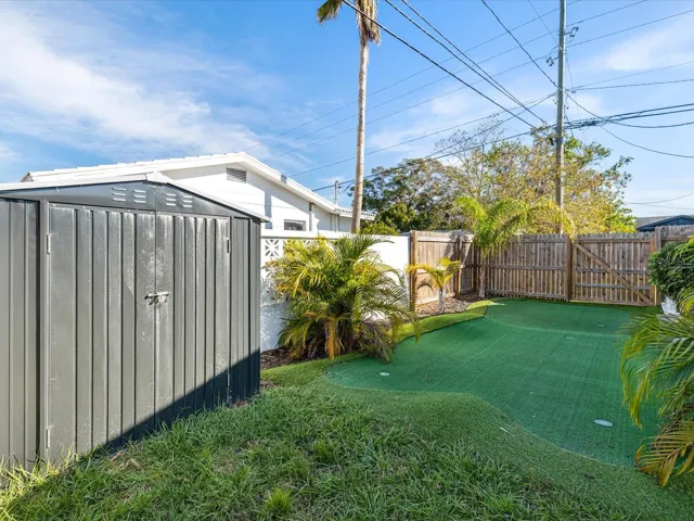 Beautifully landscaped yard with putting green and storage shed