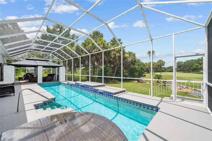 The screened Lap pool w/WATERFALL area offers generous deck space and an open view toward the surrounding green space and golf course.